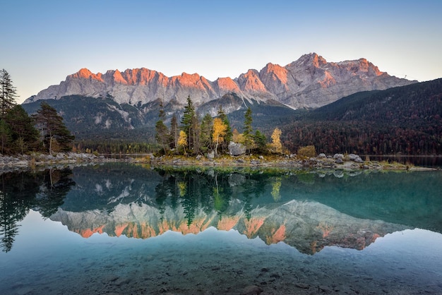 Scenic view of lake by mountains against clear sky during sunset