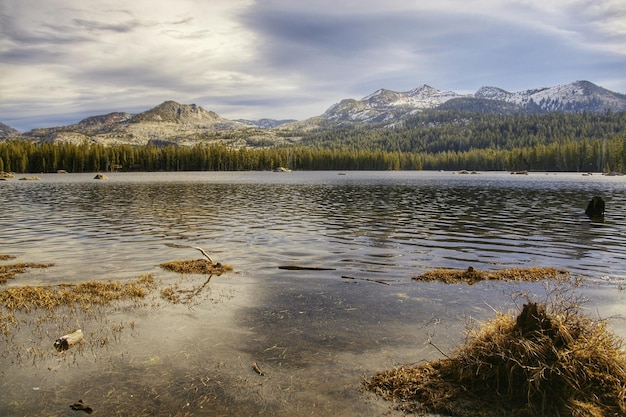 Scenic view of lake by mountains against cloudy sky