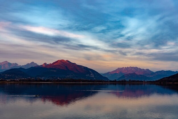 Scenic view of lake by mountains against sky during sunset