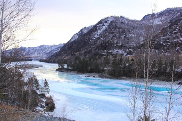 Scenic view of lake by snowcapped mountains against sky