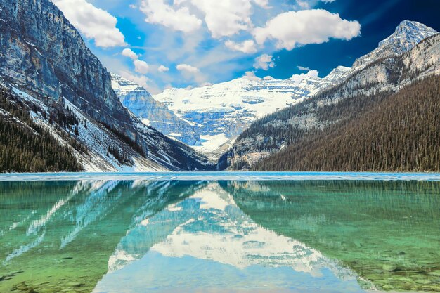 Scenic view of lake by snowcapped mountains against sky