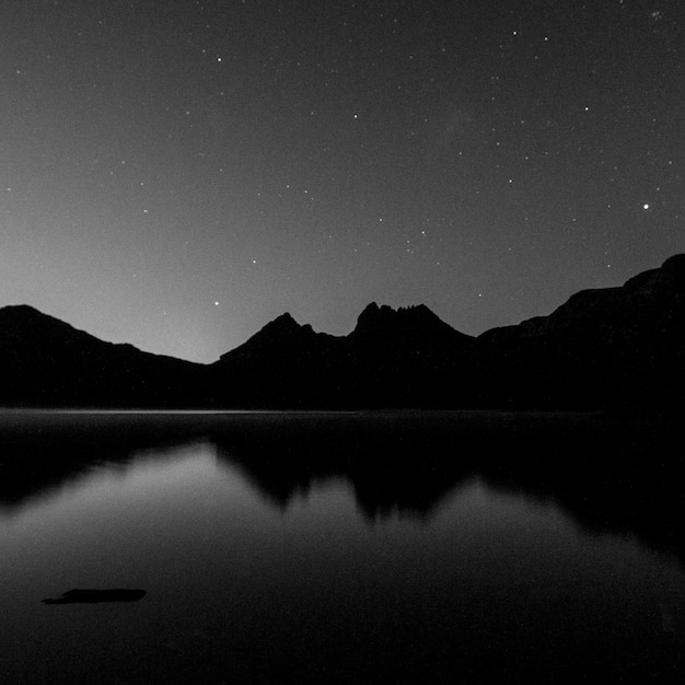 Широкий вид на озеро и горный хребет на фоне ночного неба