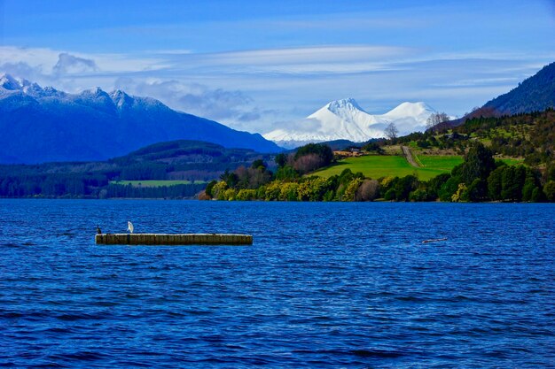 Scenic view of lake and mountains against blue sky