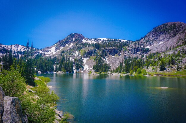 Scenic view of lake and mountains against clear blue sky