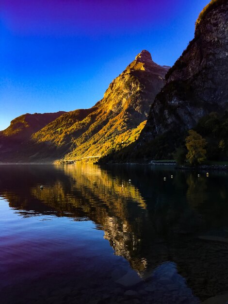 Scenic view of lake and mountains against clear blue sky