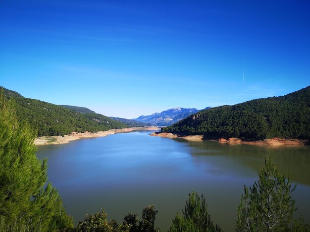 Scenic view of lake and mountains against clear blue sky