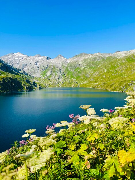 Scenic view of lake and mountains against clear blue sky