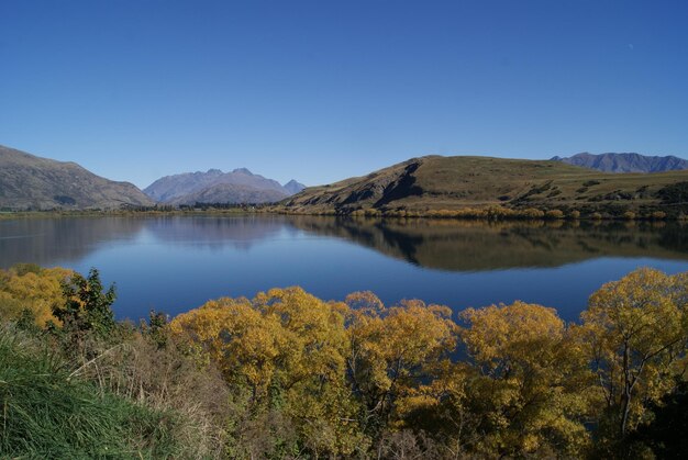 Scenic view of lake and mountains against clear blue sky