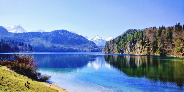 Scenic view of lake and mountains against clear blue sky