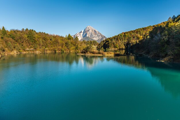 Scenic view of lake and mountains against clear blue sky