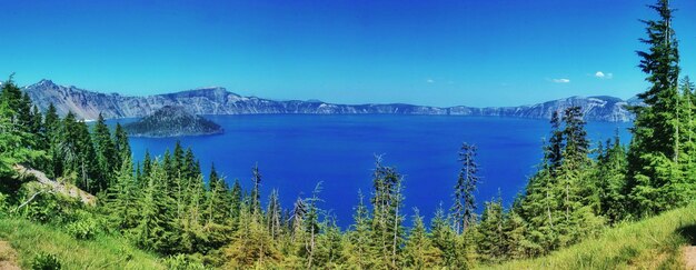 Scenic view of lake and mountains against clear blue sky