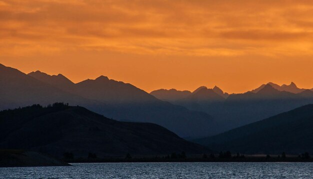 Scenic view of lake and mountains against sky during sunset