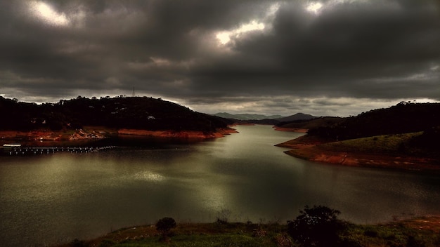 Scenic view of lake and mountains against storm clouds