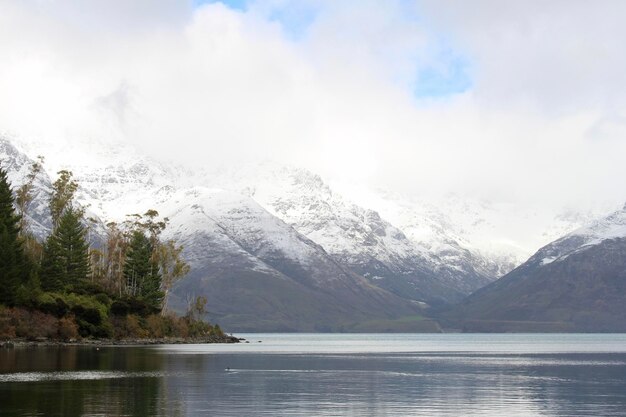 Photo scenic view of lake and snowcapped mountains against cloudy sky