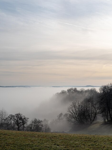 Photo scenic view of landscape against sky during foggy weather