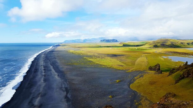 Scenic view of landscape by sea against sky