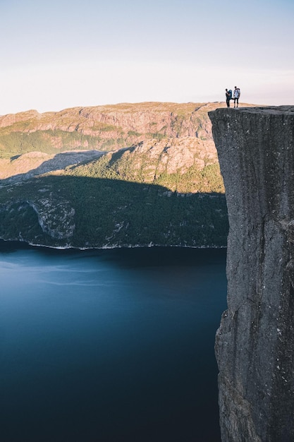 Foto vista panoramica della montagna e del lago con gli uomini sulla roccia contro il cielo