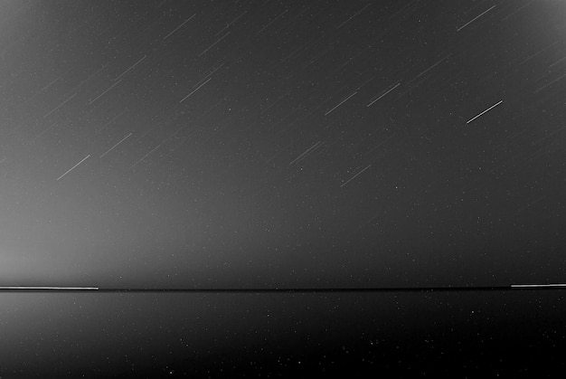Фото Пейзажный вид на спокойное озеро на фоне звездных следов ночью