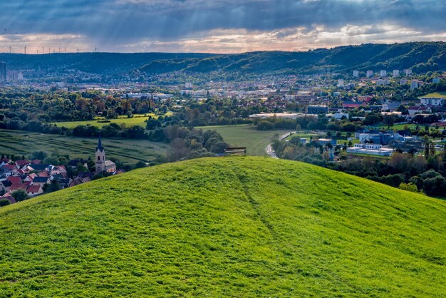 写真 空に照らされた建物によるフィールドの景色