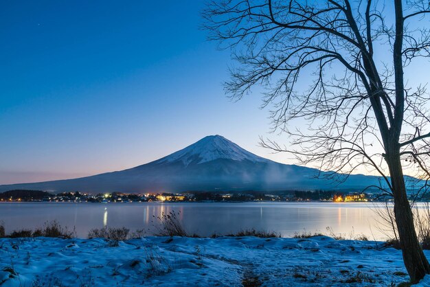 写真 青い空を背景に雪に覆われた山々から湖の景色