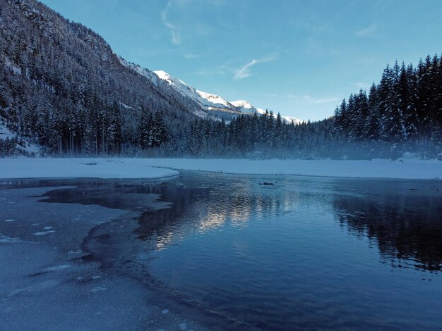 写真 空に照らされた雪に覆われた山々から湖の景色