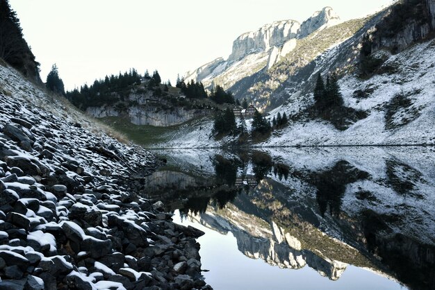 写真 空に照らされた雪に覆われた山々から湖の景色