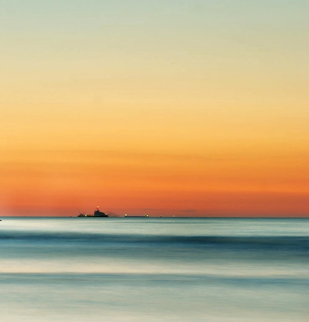 写真 オレンジ色の空を背景に海の景色