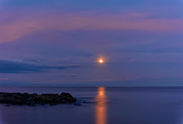 사진 달이 뜨는 동안 하늘을 배경으로 바다를 바라보는 풍경