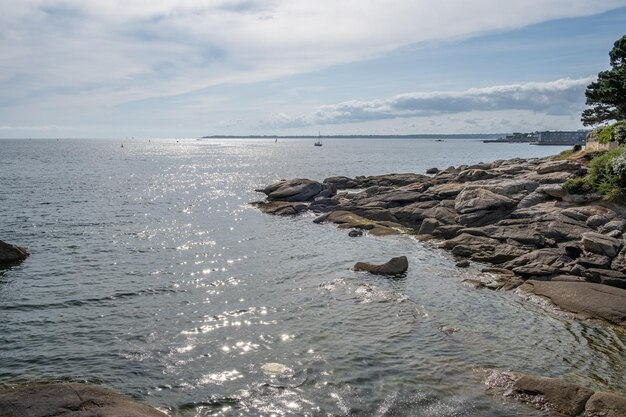 写真 空を背景に岩石の海岸線のある海の景色