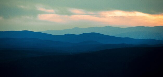 写真 夕暮れ の 空 に 照らさ れ て いる 山 の シルエット の 景色