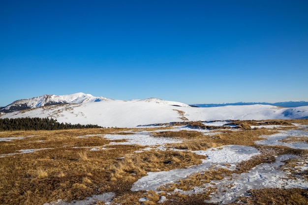 写真 晴れた青い空に照らされた雪に覆われた山の景色