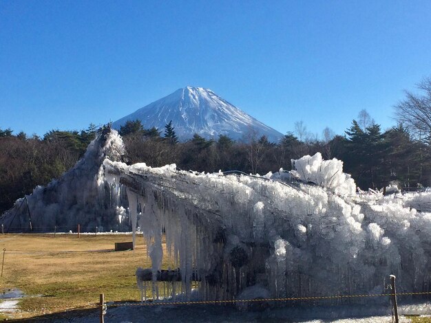 写真 晴れた青い空に照らされた雪に覆われた山の景色