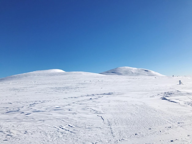 写真 晴れた青い空に照らされた雪に覆われた山の景色