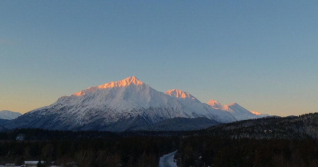 写真 晴れた空を背景に雪に覆われた山の景色