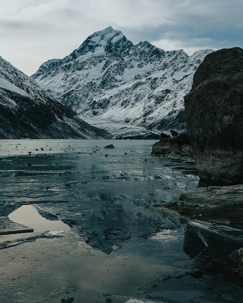 写真 空と氷の湖を背景に雪に覆われた山々の風景