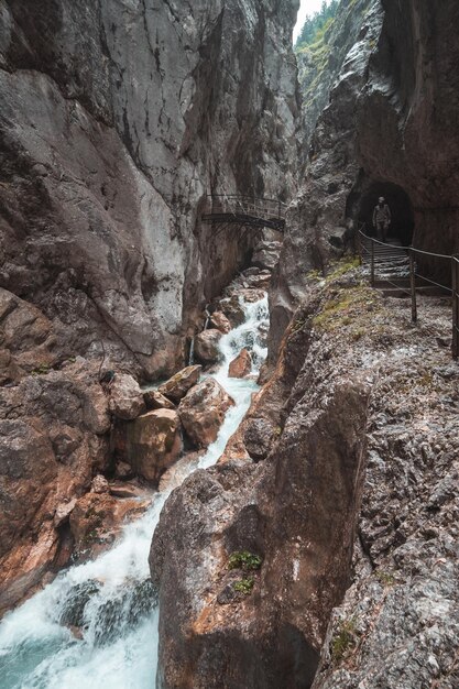 Фото Красивый вид на водопад с человеком, выходящим из пещеры по скальной формации