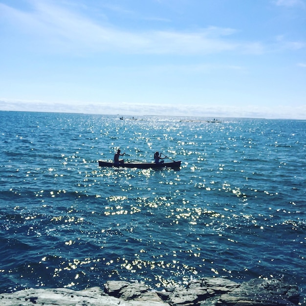 Photo scenic view of people in boat on sea against blue sky