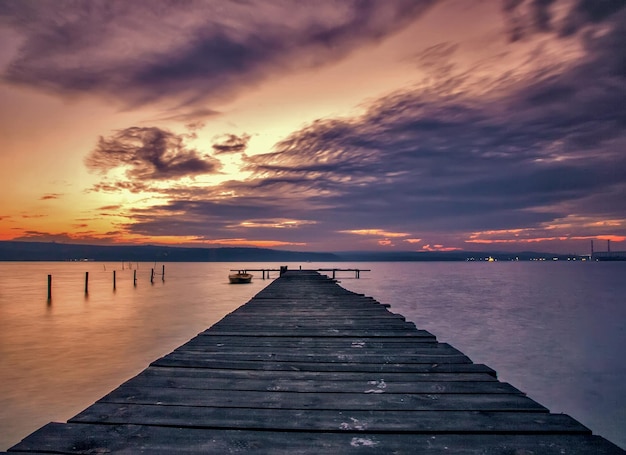 Scenic view of pier over sea against cloudy sky during sunset