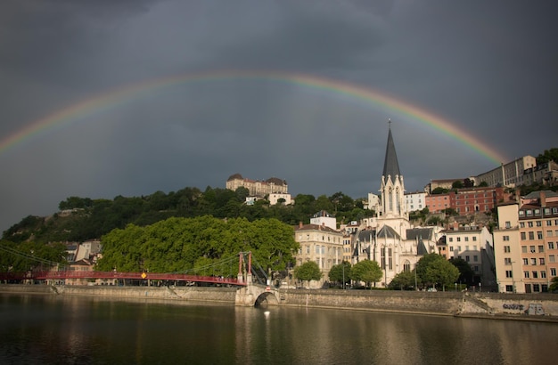 Scenic view of rainbow over river and buildings in lyon city