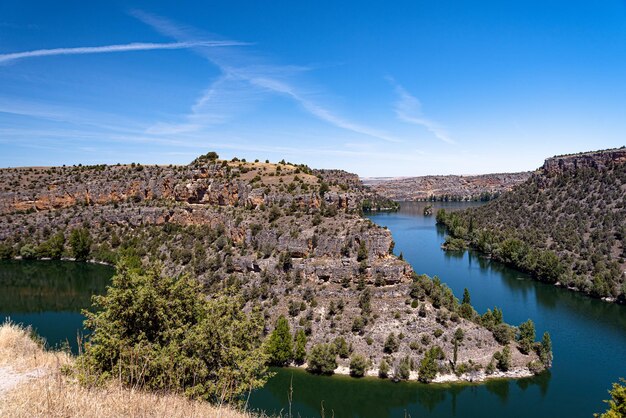 Scenic view of river by mountains against blue sky