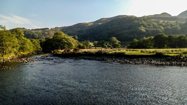 Scenic view of river by mountains against sky