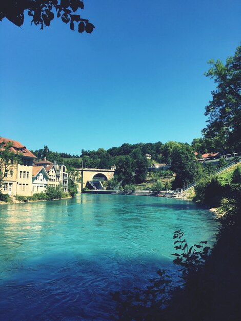 Scenic view of river by town against clear blue sky