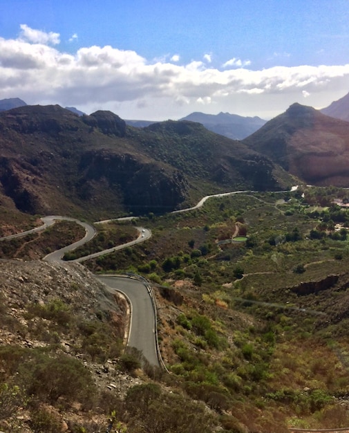 Scenic view of road by mountains against sky