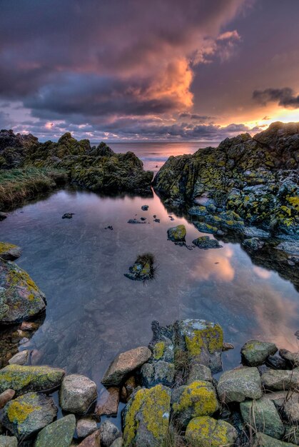 Photo scenic view of a rockpool against sky during sunrise