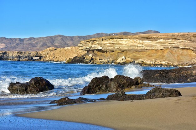 Scenic view of rocks on beach against clear blue sky