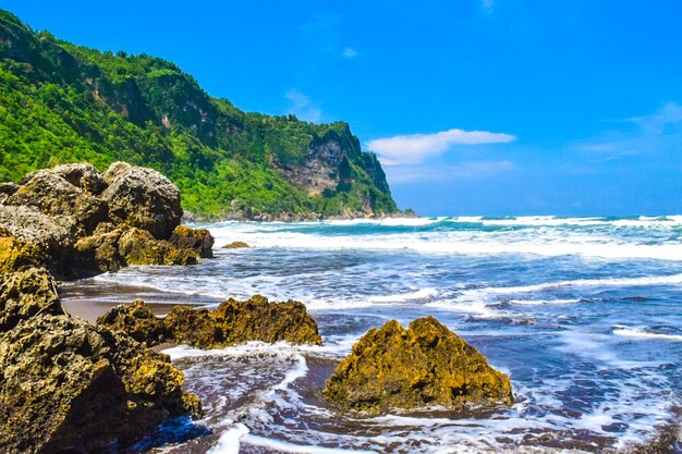 Scenic view of rocks in sea against blue sky