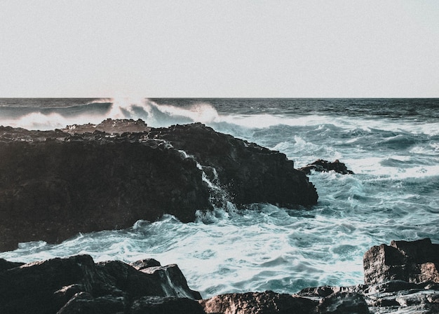 Photo scenic view of rocks in sea against clear sky