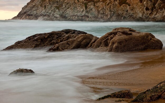 Photo scenic view of rocks in sea against sky