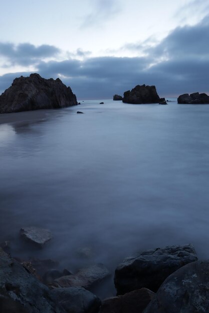 Photo scenic view of rocks in sea against sky