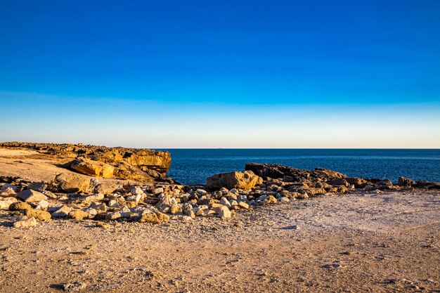 Scenic view of rocky beach against blue sky